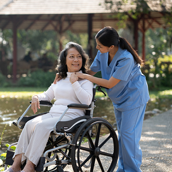 Caregiver supporting a smiling patient outdoors